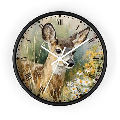 A round wall clock with a black frame and a printed illustration of a deer in tall grass beside white and yellow flowers. The clock face has black Roman numerals and white hands, shown against a plain white background.