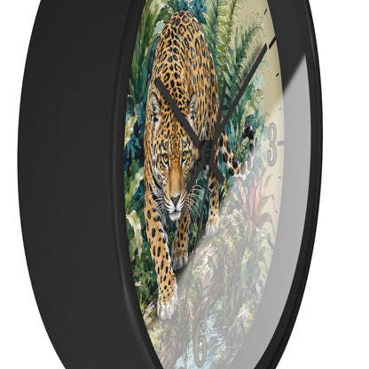 A round wall clock with a black frame and a printed face showing a large spotted big cat walking through dense green foliage. The clock is photographed against a plain white background.