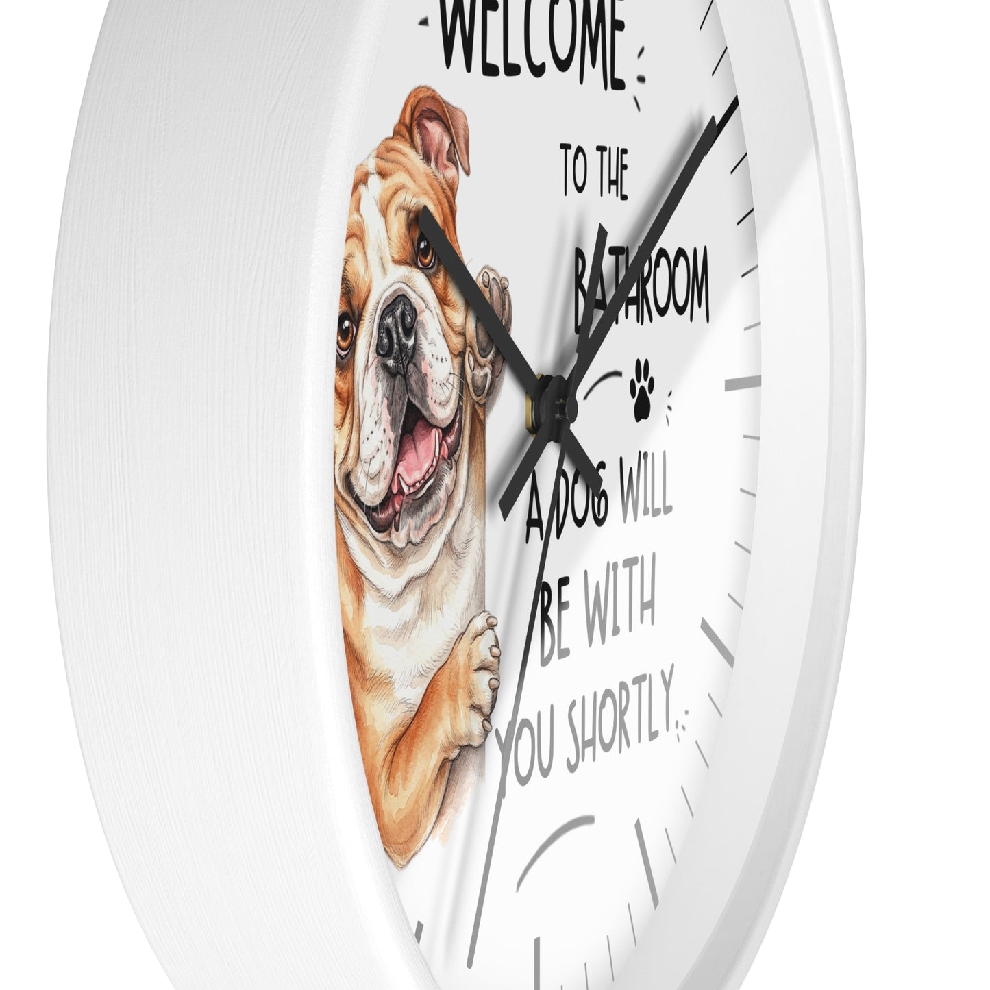 A white round wall clock with a humorous dog-themed design. The clock face features a detailed illustration of a brown and white bulldog peeking from behind text that reads 'WELCOME TO THE BATHROOM A DOG WILL BE WITH YOU SHORTLY.