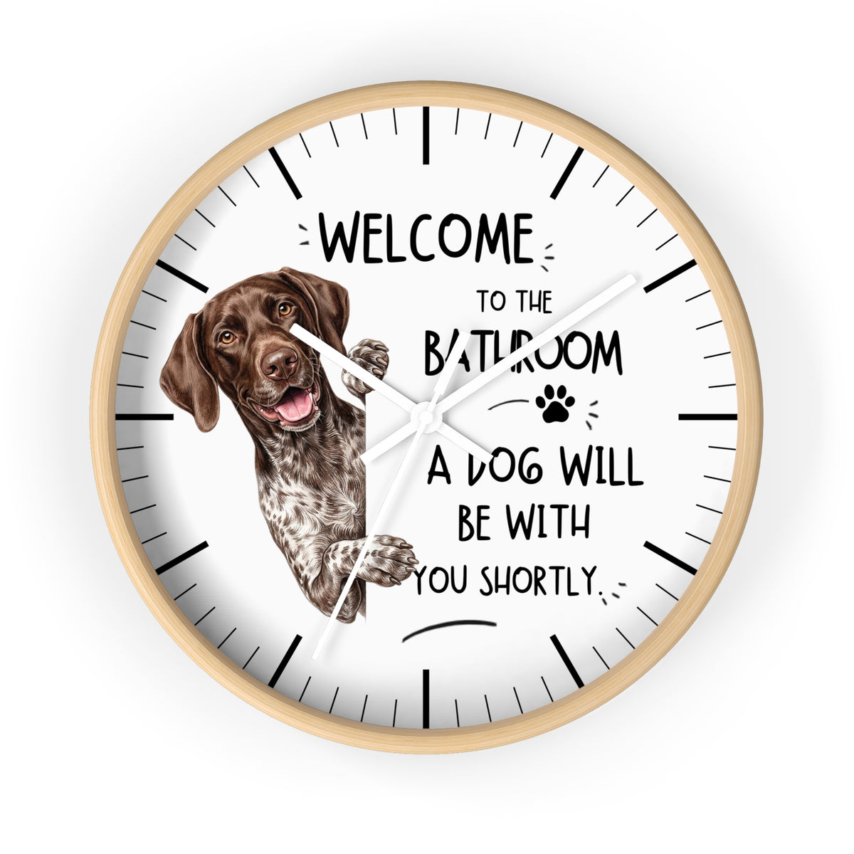 A round wall clock with a light wood frame and a white face, featuring a brown and white German Shorthaired Pointer dog illustration and the humorous text 'WELCOME TO THE BATHROOM A DOG WILL BE WITH YOU SHORTLY.' The clock is shown against a plain white background.
