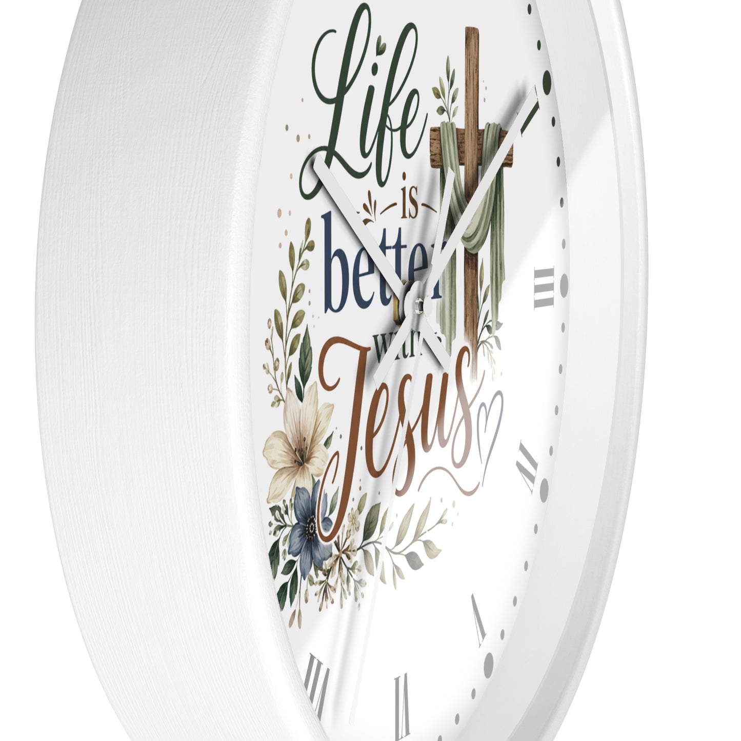 A white round wall clock with a religious design featuring the words 'Life is better with Jesus' in decorative script, a wooden cross with a green cloth, and floral illustrations.