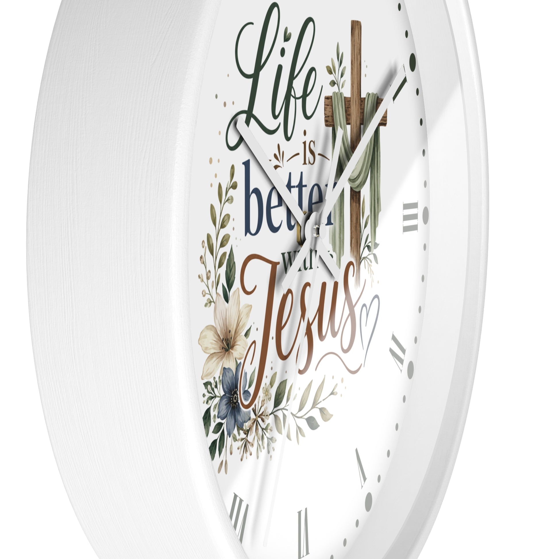 A white round wall clock with a religious design featuring the words 'Life is better with Jesus' in decorative script, a wooden cross with a green cloth, and floral illustrations.