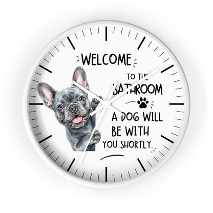 A round white wall clock with black hands and hour markers, featuring a French bulldog illustration and the text 'WELCOME TO THE BATHROOM A DOG WILL BE WITH YOU SHORTLY.' on a white background.