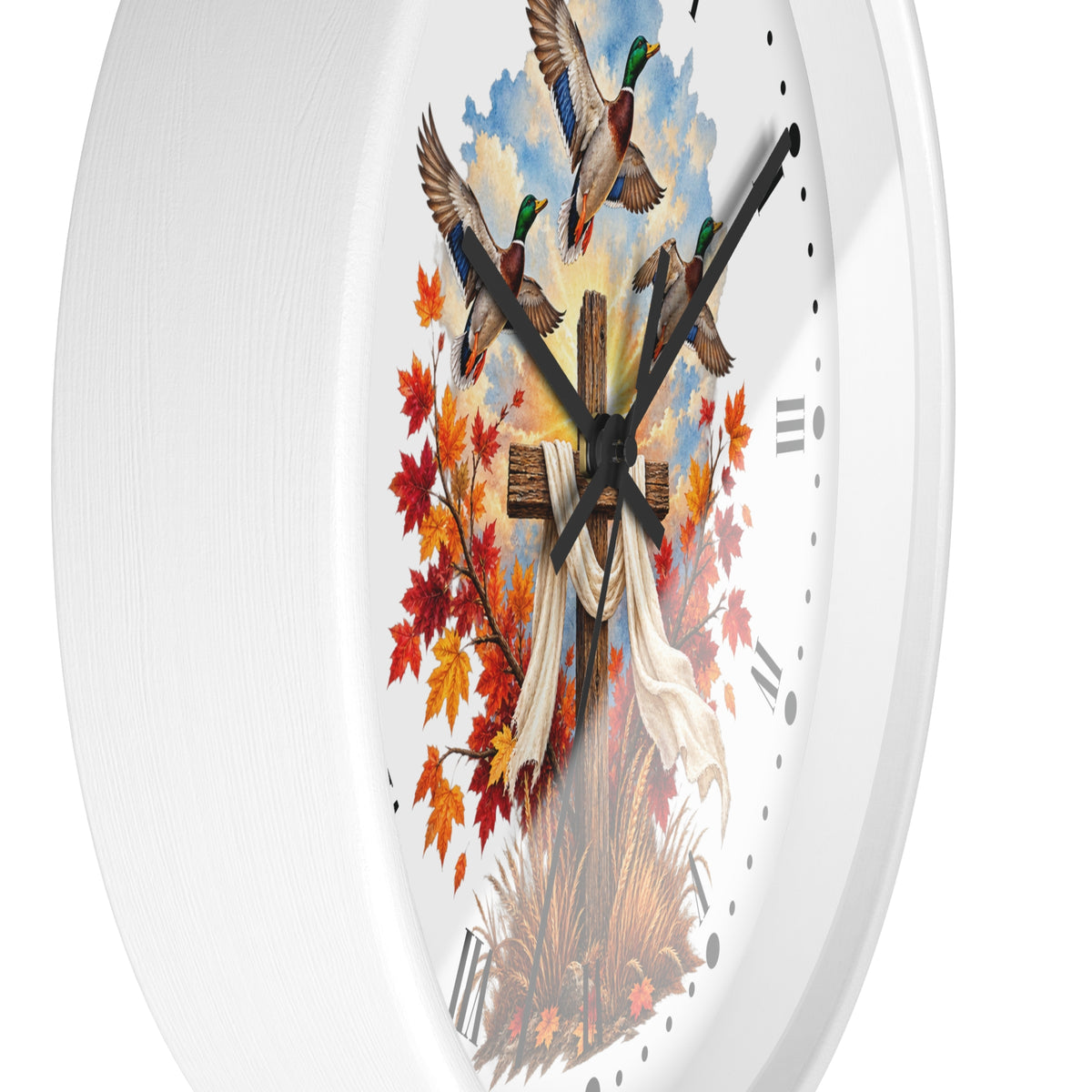 A white oval wall clock with a detailed autumn-themed illustration on the face, featuring three mallards flying above red and orange fall leaves, a wooden cross, and a white cloth, set against a clean white background.