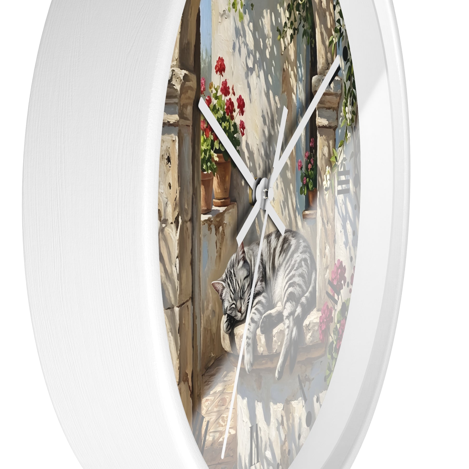 Round white wall clock with a printed illustration of a gray tabby cat lounging on a stone ledge under warm sunlight, with red flowers and green vines in the background.