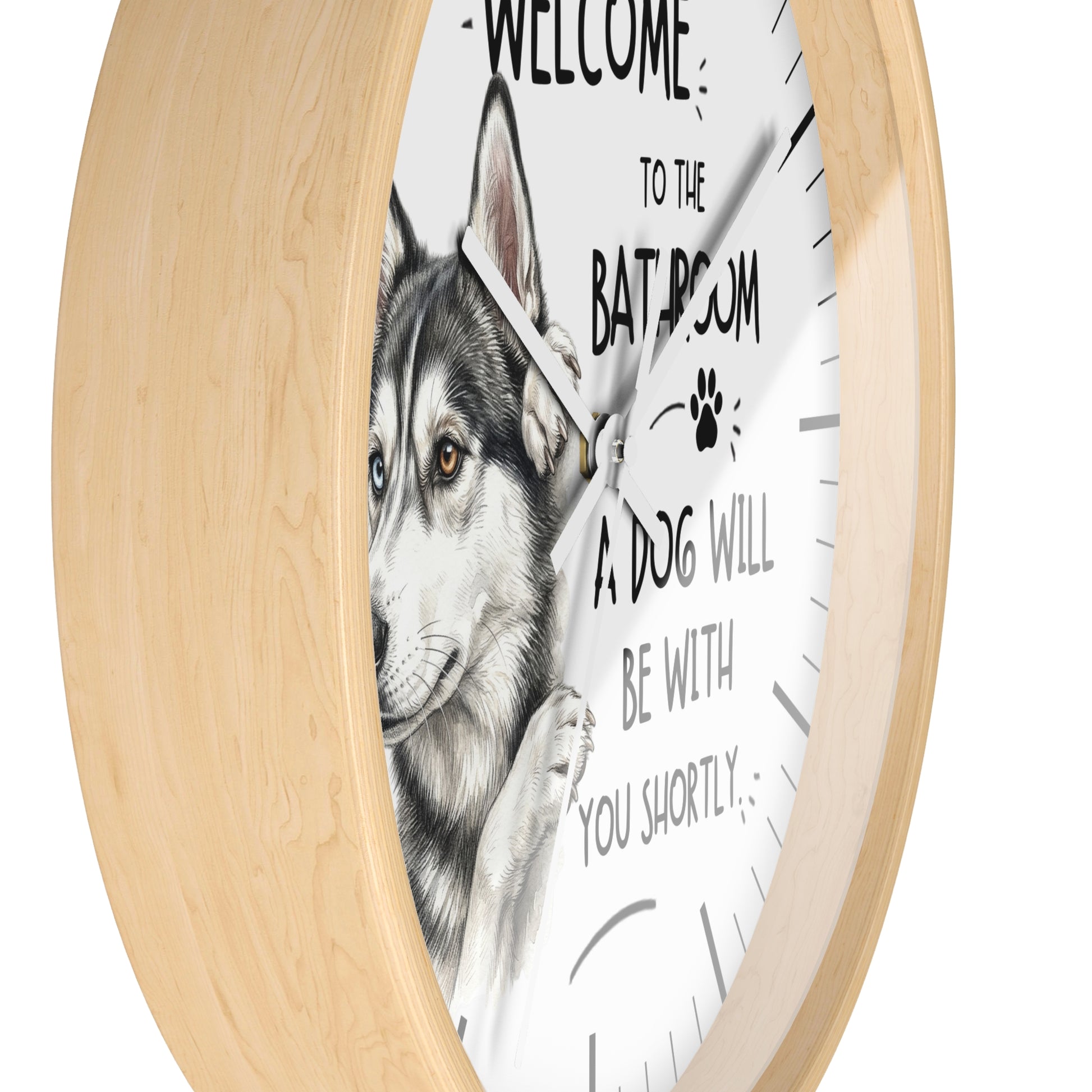 A round wall clock with a light natural wood frame and a white face featuring a detailed illustration of a husky dog and the text 'WELCOME TO THE BATROOM A DOG WILL BE WITH YOU SHORTLY'.