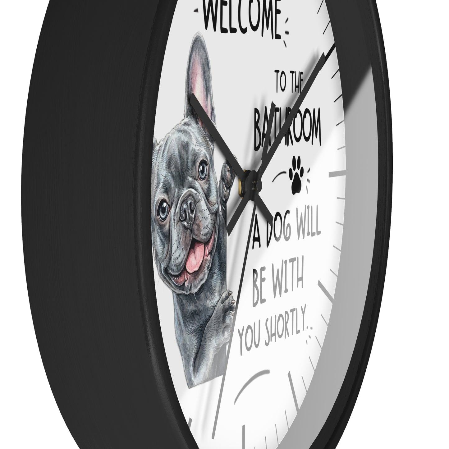 A round wall clock with a black frame and white face, featuring a French bulldog illustration and the text 'WELCOME TO THE BATHROOM A DOG WILL BE WITH YOU SHORTLY.'.