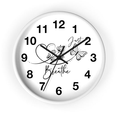 A round white wall clock with black Arabic numerals and black hands, featuring butterfly and floral illustrations with the words 'Just Breathe' on the clock face, shown against a plain white background.