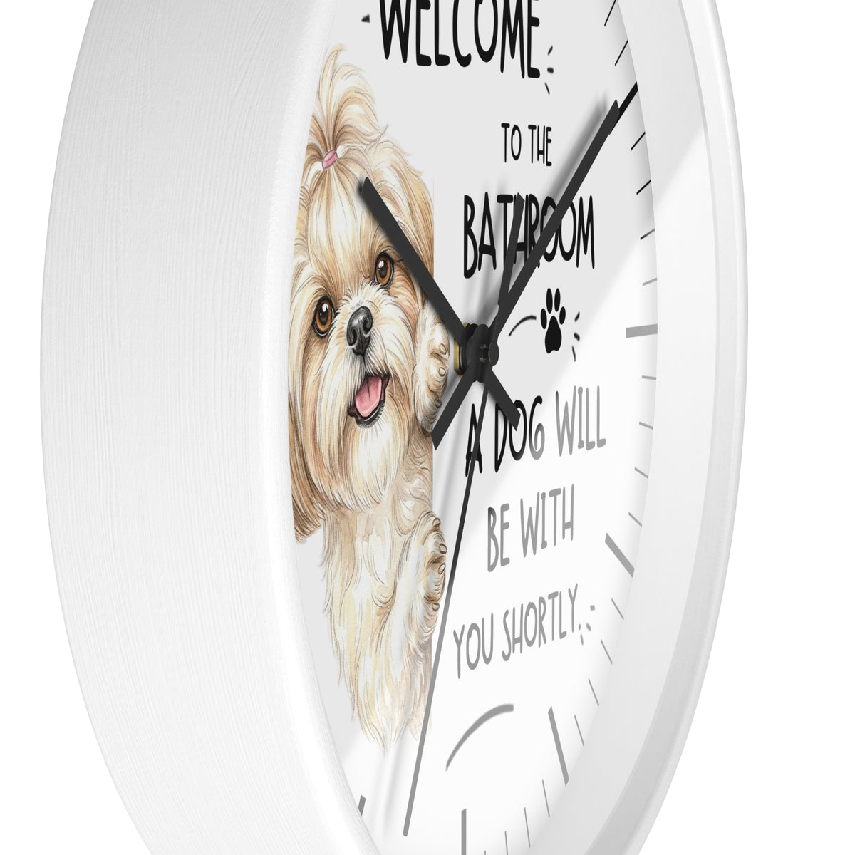 A round white wall clock with a printed illustration of a small fluffy dog and the text 'WELCOME TO THE BATHROOM A DOG WILL BE WITH YOU SHORTLY' on a clean white background.