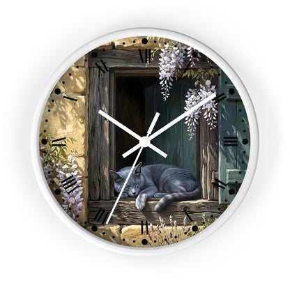 A round wall clock with a white frame and a printed illustration of a gray cat sleeping on a rustic wooden windowsill, surrounded by wisteria flowers and stone-textured numerals, shown against a plain white background.