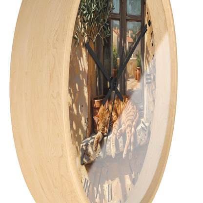 Round wall clock with a light natural wood frame and a printed scene of an orange tabby cat lying on a stone ledge in front of a window.