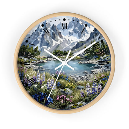 A round wall clock with a light natural wood frame, featuring a scenic landscape print of a mountain lake surrounded by wildflowers, set against a plain white background.