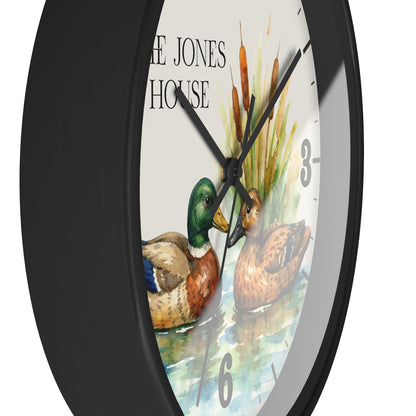 A close-up of a wall clock with a black frame and a white face featuring a watercolor illustration of two ducks, cattails, and the text 'THE JONES HOUSE'.