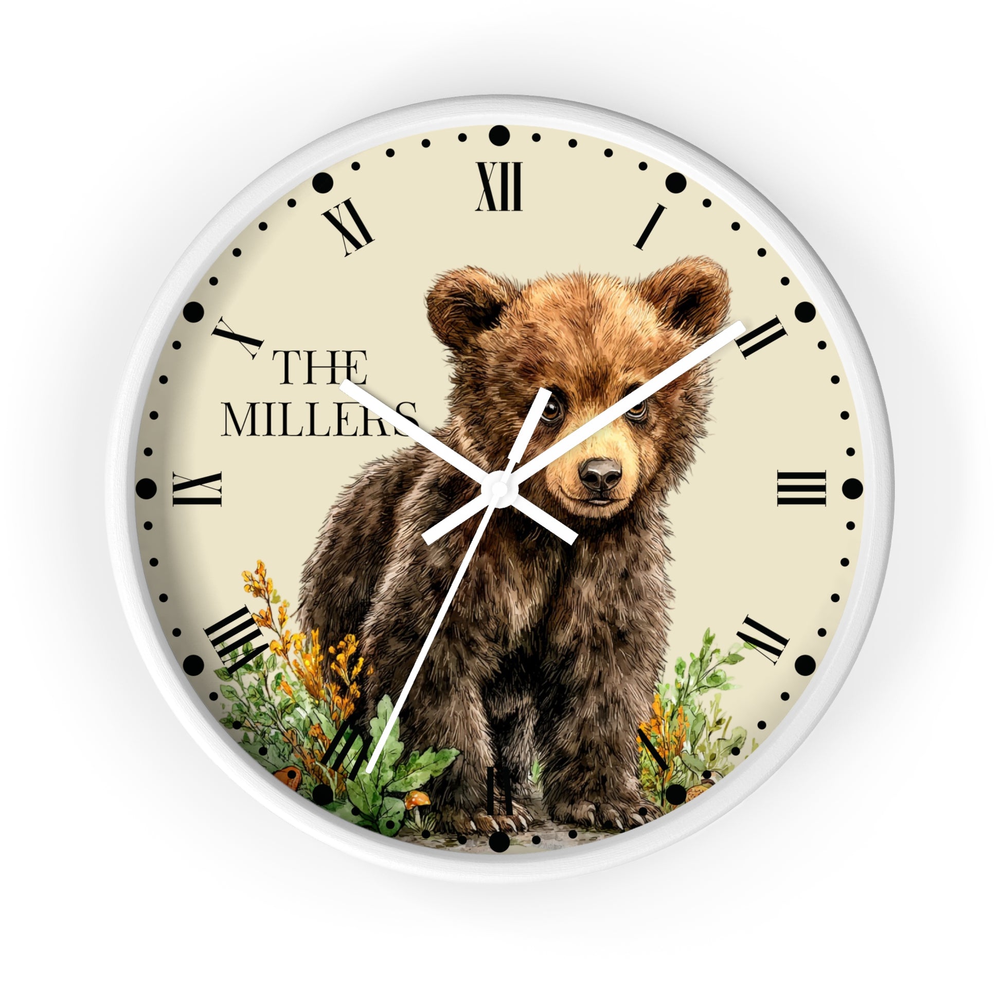 A round wall clock with a white frame and a cream-colored face featuring a watercolor illustration of a brown bear cub, Roman numerals, black hands, and the text 'THE MILLERS' near the 10 o'clock position.