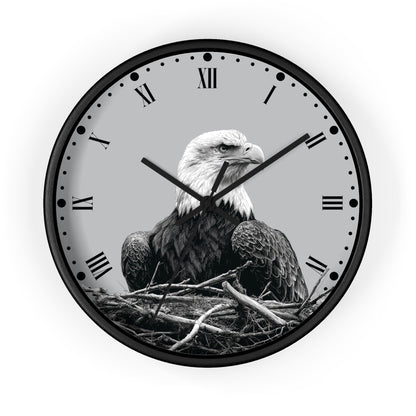 Round wall clock with a black frame and a grayscale bald eagle perched in a nest on the clock face, with Roman numerals and black hands on a light gray background.
