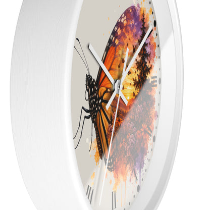 A round wall clock with a white frame and a printed dial featuring a large orange and black butterfly over a watercolor-style floral background in purple, orange, yellow, and brown tones.