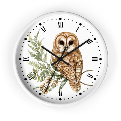 A round white wall clock with a detailed illustration of a brown owl perched on a green leafy branch. The clock face features black Roman numerals, black hour and minute hands, and black minute markers.