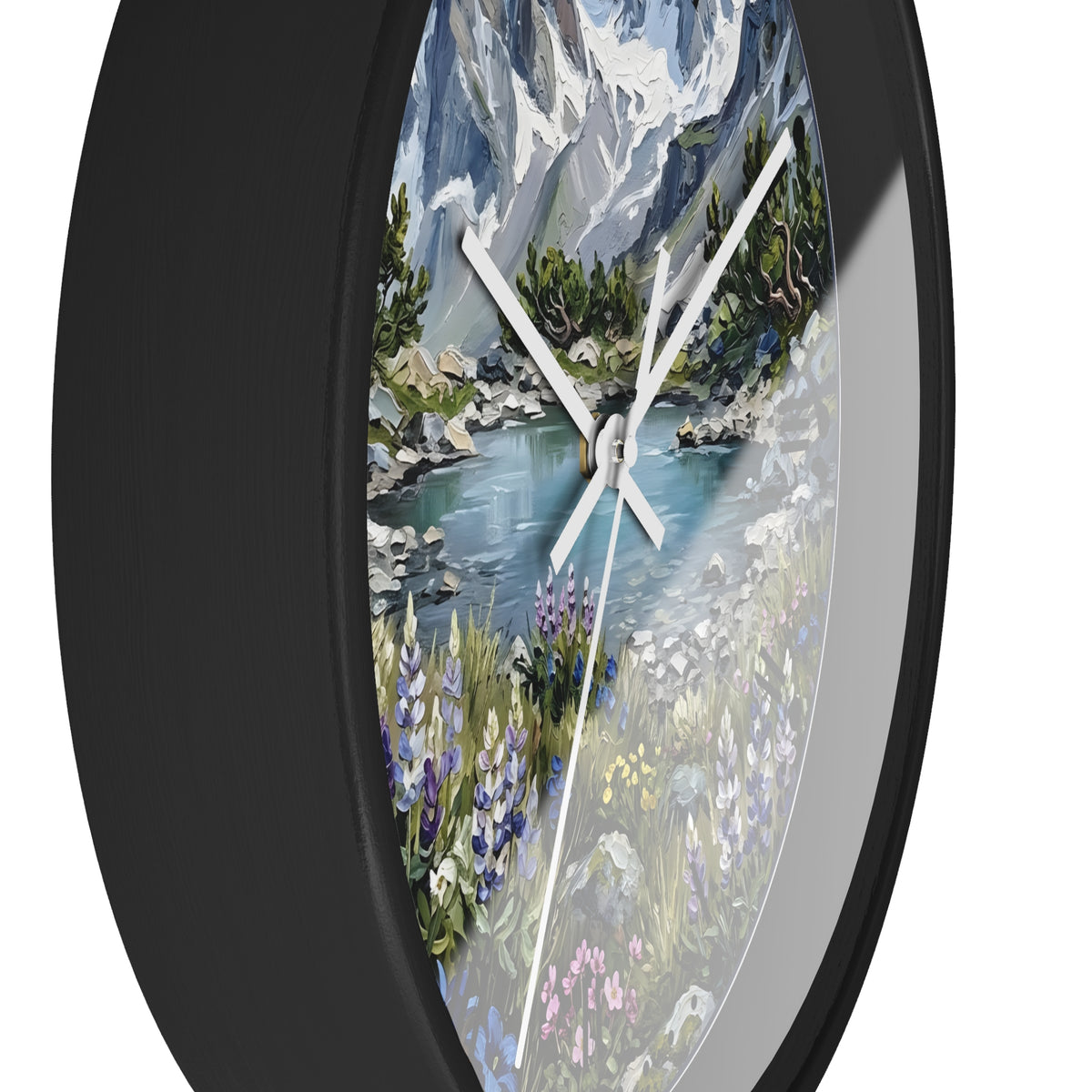 A round wall clock with a black frame and a scenic landscape print featuring a mountain lake, trees, and wildflowers. The clock is shown at an angle against a plain white background.