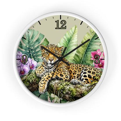 A round wall clock with a white frame and a tropical jungle design featuring a leopard resting on a branch among green leaves and pink flowers. The clock face has a light beige background with black Arabic numerals and hands.