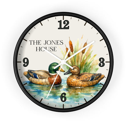 A round wall clock with a black frame and a printed dial showing two mallards on water, cattails, and the text 'THE JONES HOUSE' at the upper left. The clock is photographed against a plain white background.