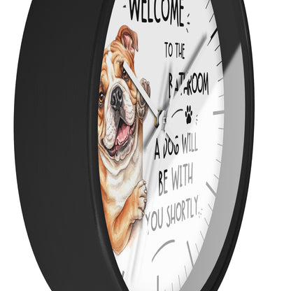 A round wall clock with a black frame and a white face featuring an illustration of a bulldog and the text 'WELCOME TO THE BATHROOM A DOG WILL BE WITH YOU SHORTLY'.