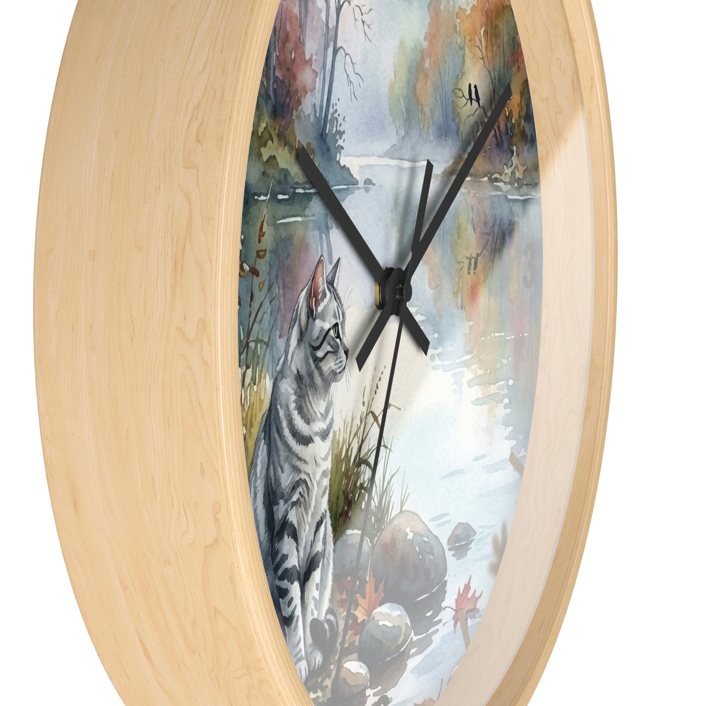 Oval wall clock with a light natural wood frame and a printed illustration of a gray tabby cat beside a reflective water scene with autumn trees.
