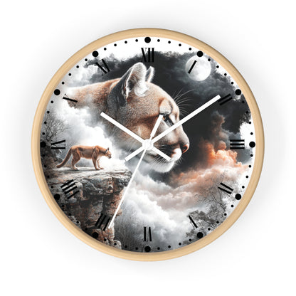 A round wall clock with a light wood frame, featuring a surreal printed design of a large cat head over a mountain landscape with a smaller cat standing on a cliff. The clock face has black Roman numerals, white hands, and a light gray background around the product.