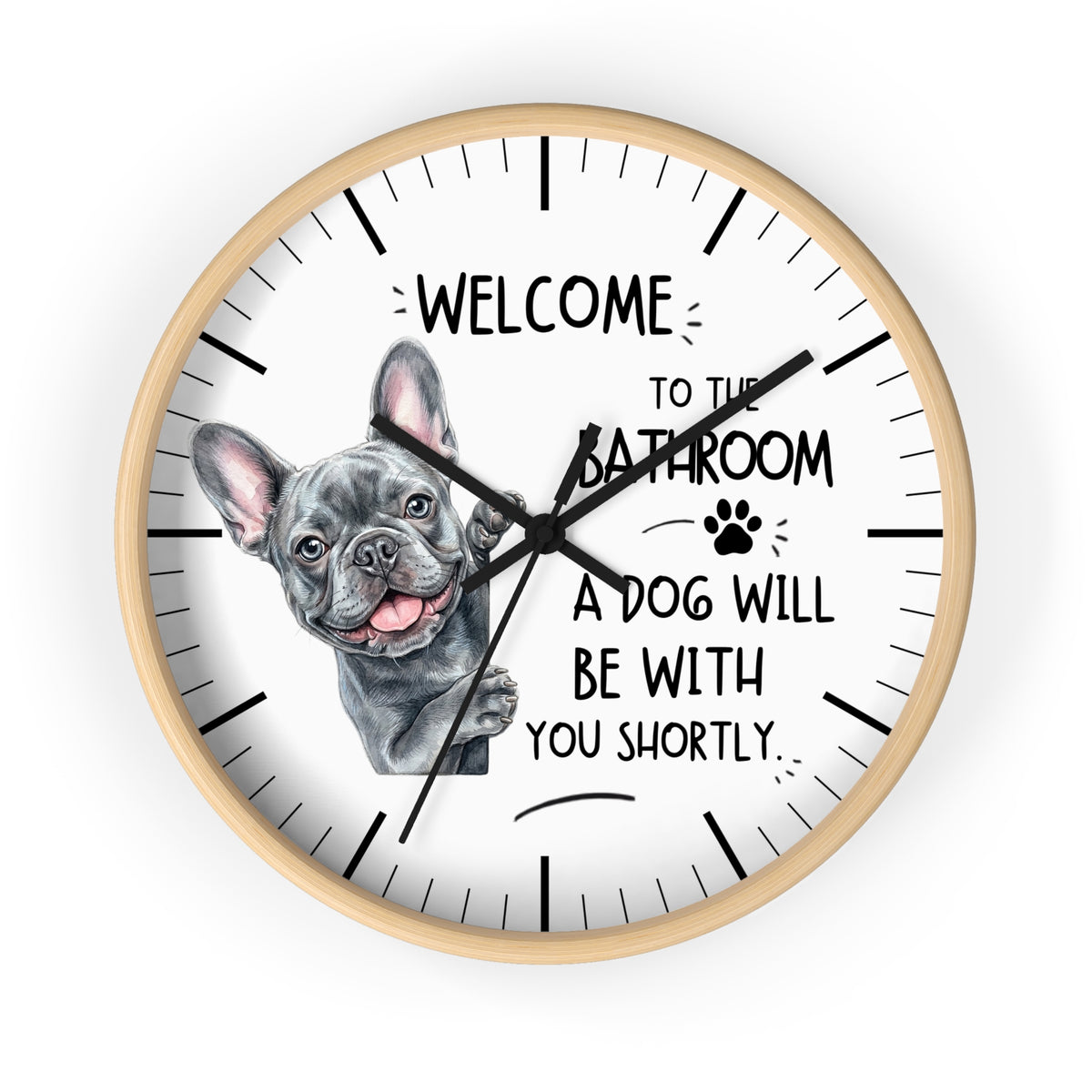 A round wall clock with a light wood frame and a white face, featuring a French bulldog illustration and the text 'WELCOME TO THE BATHROOM A DOG WILL BE WITH YOU SHORTLY.' on a plain white background.