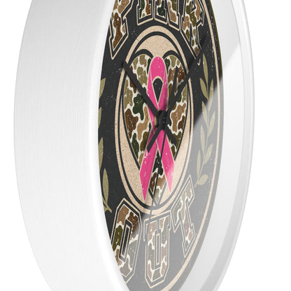 A close-up of a round wall clock with a white outer frame and a printed face featuring a pink awareness ribbon over a camouflage heart, surrounded by the words 'PINK OUT' in a distressed military-style font.