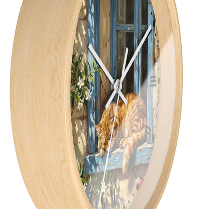 Round wall clock with a light natural wood frame and a printed illustration of an orange tabby cat resting on a blue window sill.