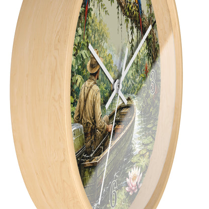 Round wall clock with a light natural wood frame and a printed scenic dial showing a man in a boat on a river surrounded by lush greenery. White clock hands and white Arabic numerals are visible against a plain white background.