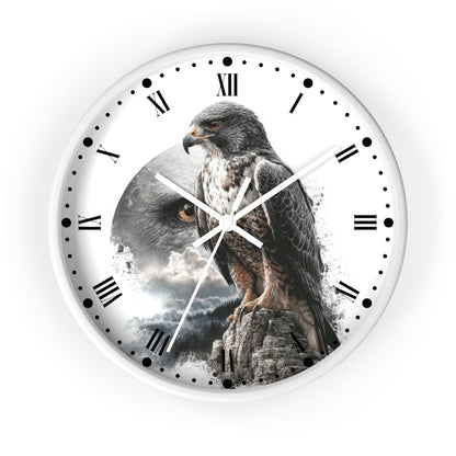 A round wall clock with a white face, black Roman numerals, and birdwatcher-style hour markers. The center features a printed design of a large hawk perched on a rock, with a cloudy sky and mountain scene behind it.