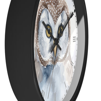 A close-up of a round wall clock with a black frame and a watercolor-style owl face printed on the dial. The owl has large yellow eyes, white and brown feathers, and a light blue lower area.