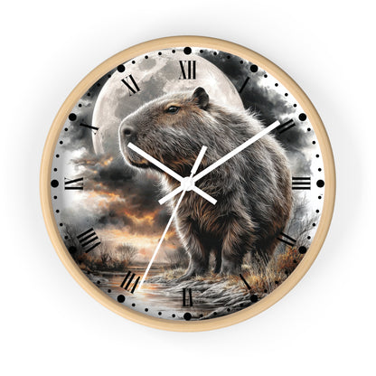 A round wall clock with a light wood frame and a printed scenic dial featuring a capybara standing in front of a large full moon and dramatic clouds. The clock face includes black Roman numerals, black hour markers with dots, and white clock hands.