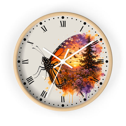 A round wall clock with a light wood frame and a cream-colored face, featuring a colorful watercolor-style design of a butterfly over a sunset landscape with trees and flowers. The clock has black Roman numerals and white hands.