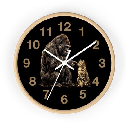 A round wall clock with a black face, gold Arabic numerals, white hands, and an illustration of a gorilla and a cat on the lower half. The clock has a light wood-toned frame and is shown against a plain white background.