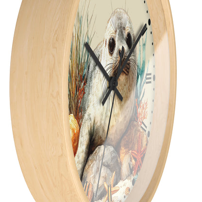 A round wall clock with a light natural wood frame and a printed center illustration of a seal on an ocean reef, shown against a plain white background.