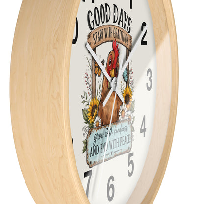 A round wall clock with a light natural wood frame and a white face featuring a colorful illustration of a rooster, flowers, and the text 'GOOD DAYS START WITH GRATITUDE' and 'grow in kindness and end with peace.'.