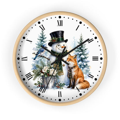 A round wall clock with a light wood frame and a white face featuring a winter holiday illustration of a snowman in a top hat, a fox, a bluebird, evergreen trees, and Roman numerals.