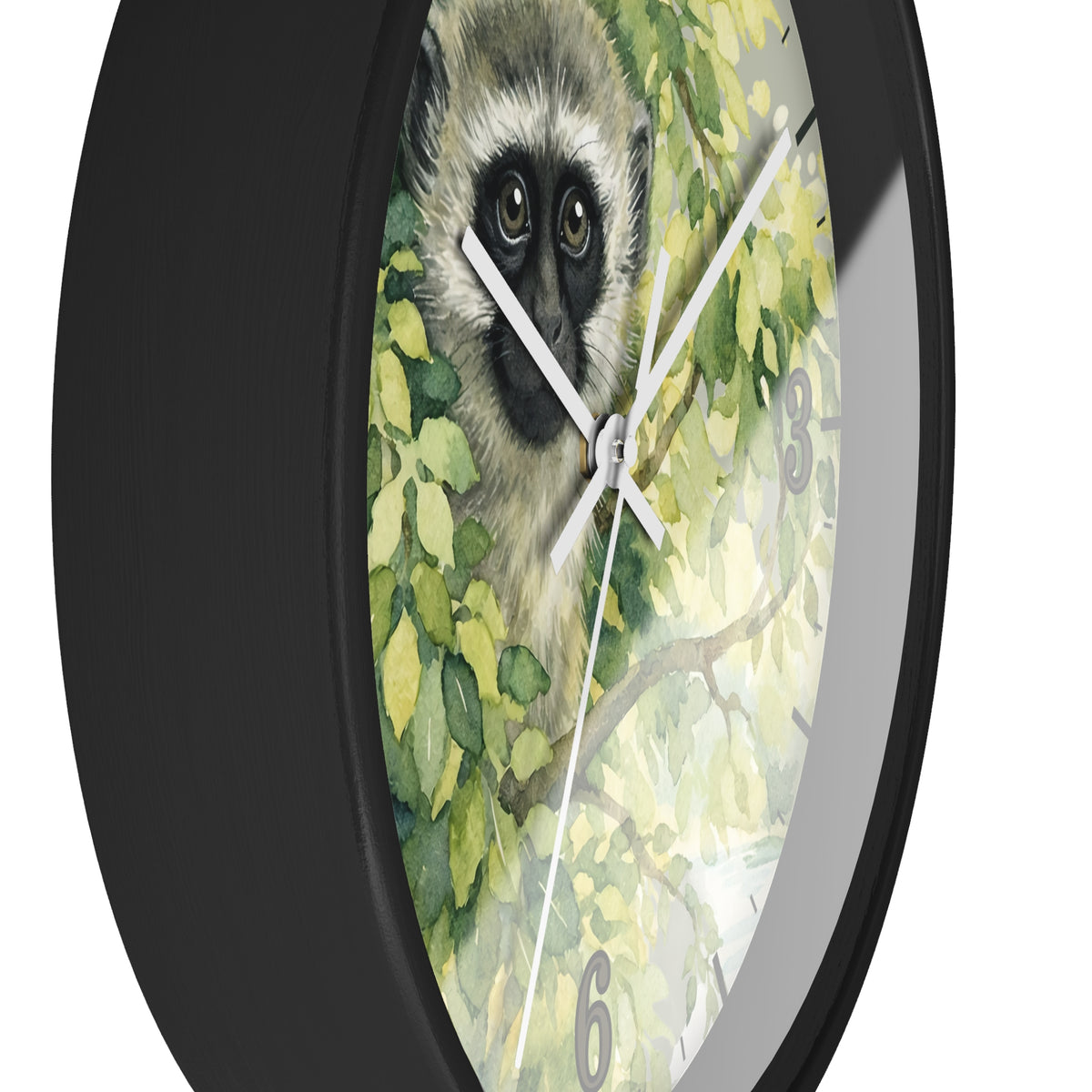 A close-up of a round wall clock with a black frame and a printed face featuring a vervet monkey surrounded by green leaves. The clock has white hands and gray numerals, shown against a plain white background.