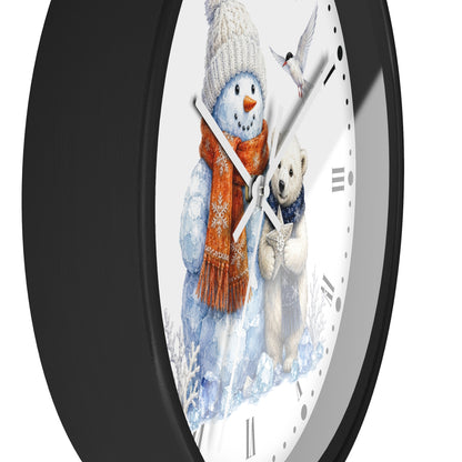 A close-up of a round wall clock with a black frame and a white face featuring a winter illustration of a snowman in a white knit hat and orange scarf next to a polar bear, with silver hands and black Roman numerals.