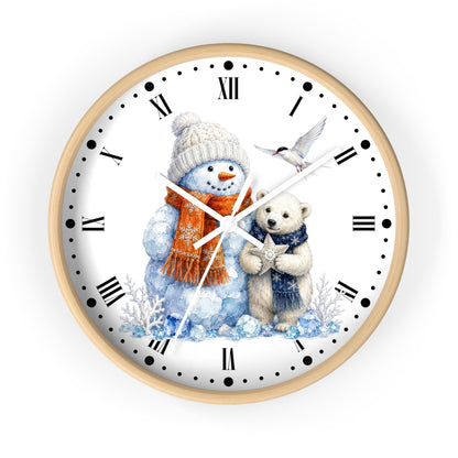 A round wall clock with a light wood frame and a white face, featuring a winter illustration of a snowman in a beige hat and orange scarf next to a white bear in a blue scarf, with black Roman numerals and hands.