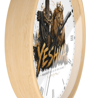 A round wall clock with a light natural wood frame and a white face featuring a crowned lion, a cross, and the word “YESHUA” in large gold lettering, shown on a white background.