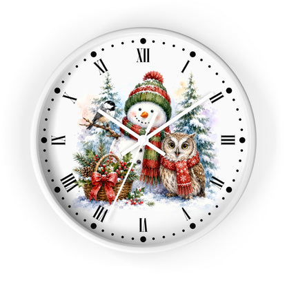 A round white wall clock with a festive Christmas illustration featuring a snowman in a red and green hat next to an owl, with snow trees and a basket in the background. The clock face has black Roman numerals, black dot hour markers, and white clock hands.