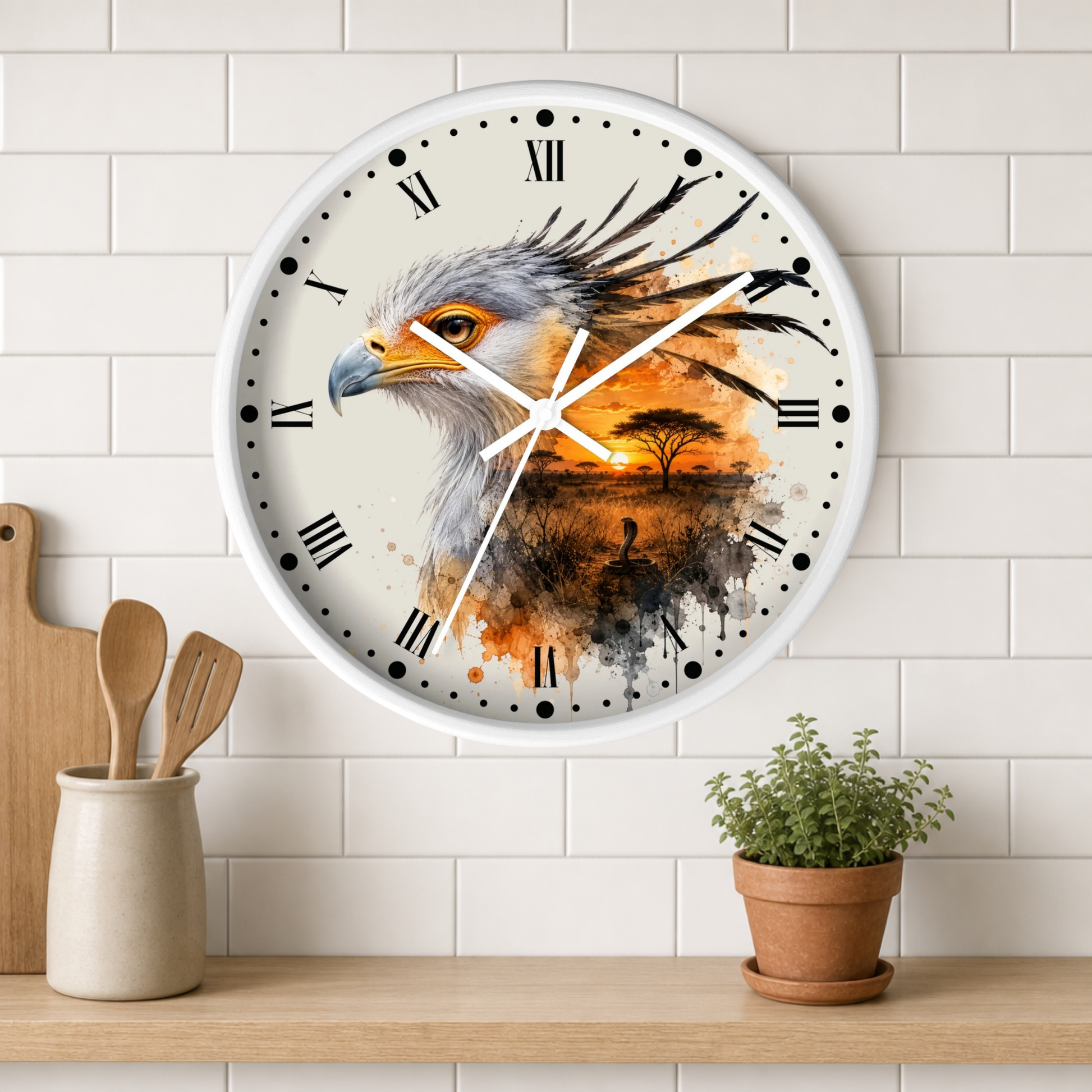 A round wall clock with a white frame hangs on a white subway-tile wall above a wooden shelf. The clock face features a detailed painting of a bird of prey in profile with an African savanna sunset scene in orange, brown, and black tones.