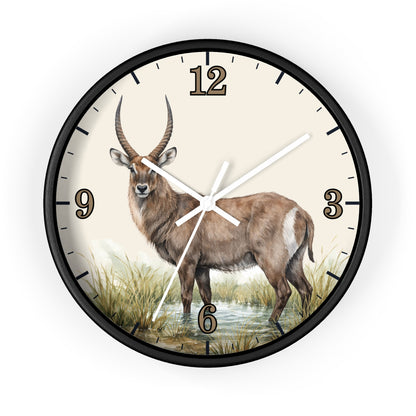 A round wall clock with a black frame and a cream-colored face featuring a painted antelope standing in grassy water. The clock has black Arabic numerals and white hands.