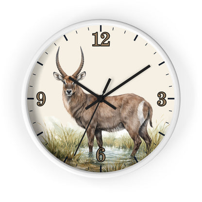 A round wall clock with a white frame and a cream-colored face featuring a detailed illustration of a waterbuck standing in grassy terrain. The clock has black hour and minute markers and black hands.