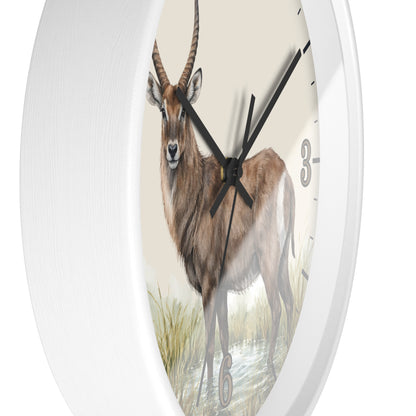A white oval wall clock featuring a detailed illustration of a brown antelope or gazelle on the clock face, with black hands and partial numerals visible against a clean white background.