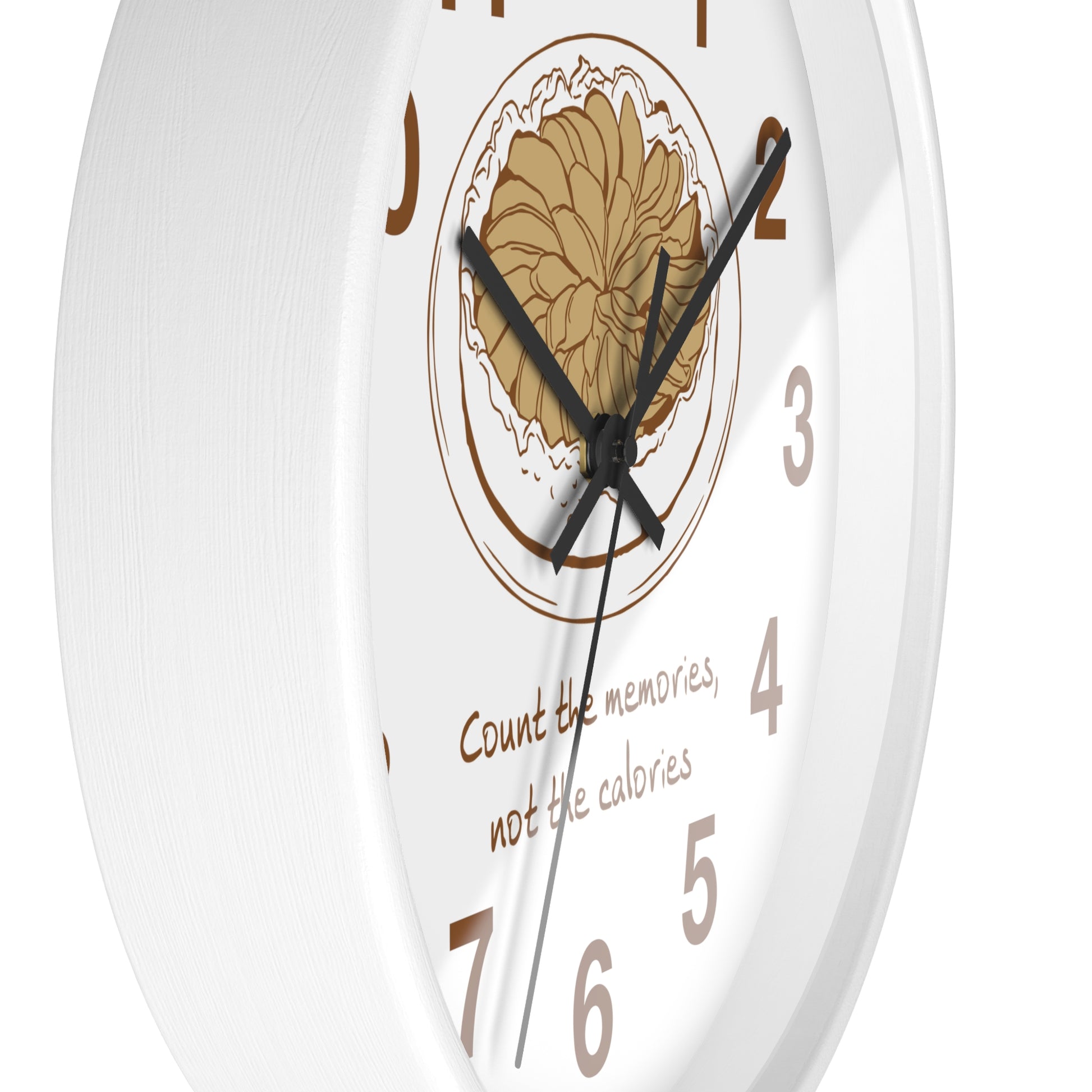 White round wall clock with a central floral illustration, black hands, brown Arabic numerals, and the phrase 'Count the memories, not the calories' on the face.