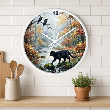 A round wall clock with a white frame hangs on a white subway tile wall above a wooden shelf. The clock face features a painted autumn forest scene with a black panther walking on rocks by a stream, two crows on a branch, and colorful fall foliage.